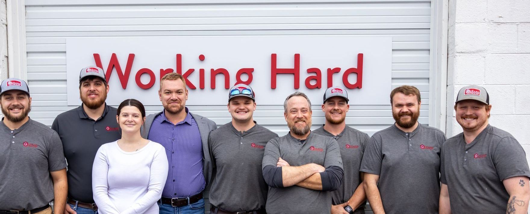 Gerard Heating and Air team in front of a Working Hard sign